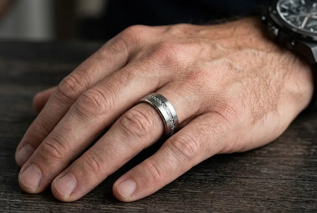 A larger man's hand wearing an 8mm brushed silver tungsten wedding band, naturally proportioned