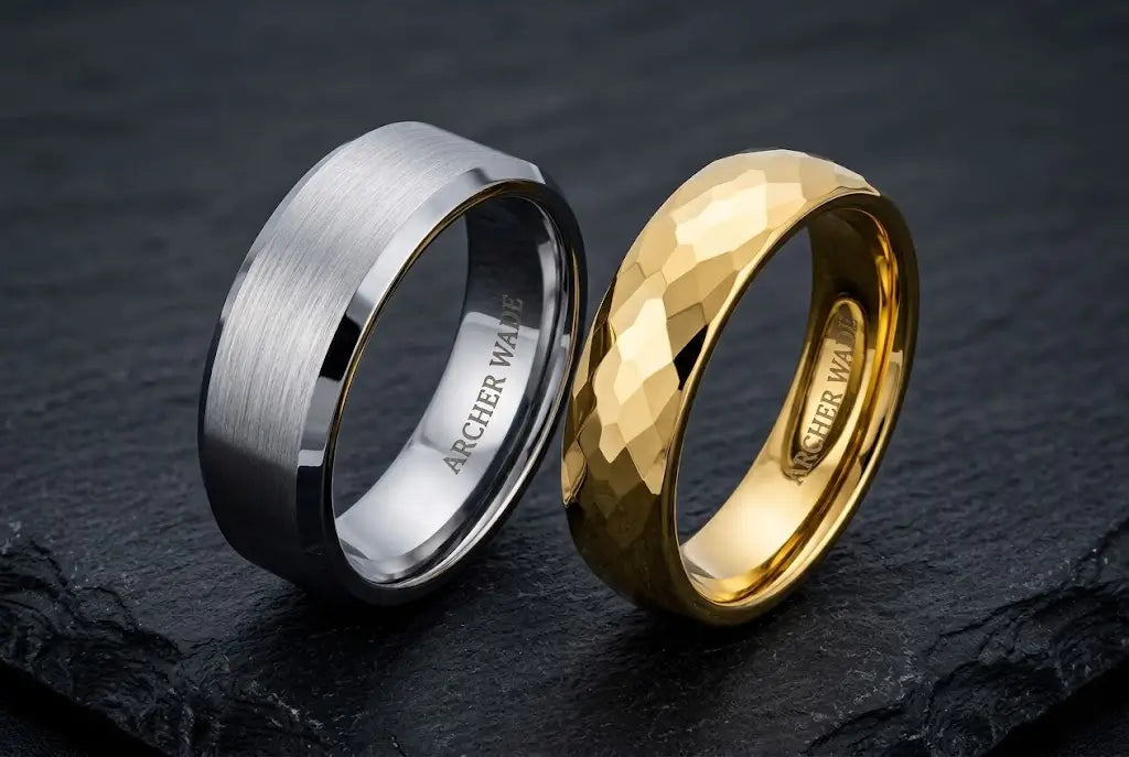 Tungsten vs gold wedding band comparison — a brushed silver tungsten band beside a polished yellow gold band on dark slate